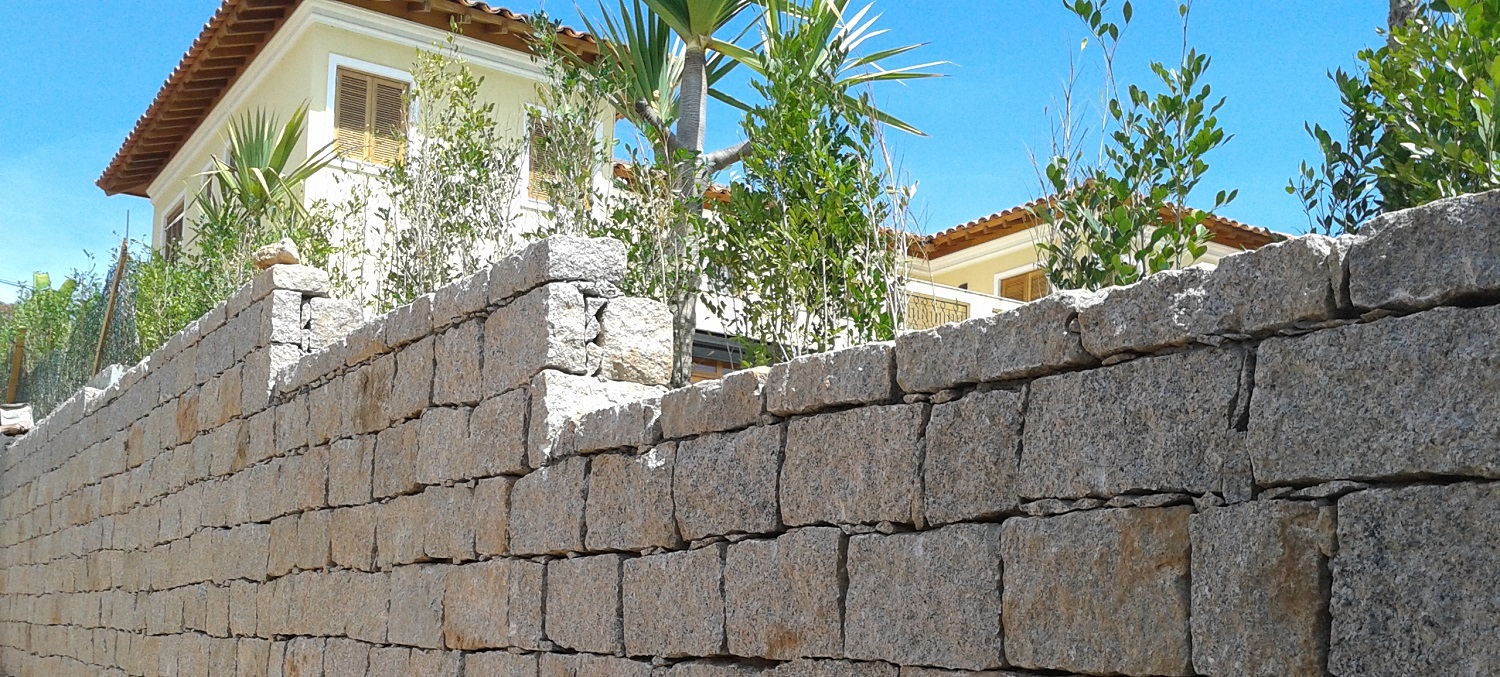 Na diferença de nível entre a rua e a casa o muro de arrimo com pedras